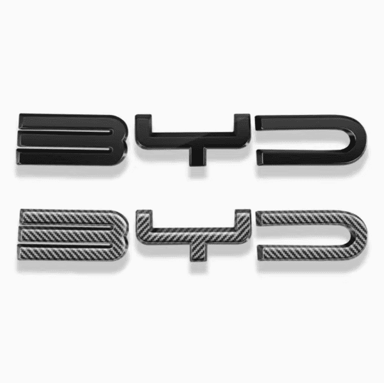 Side-by-side comparison of BYD front bumper emblem decals in gloss black and carbon fiber gray finishes for Sealion 6