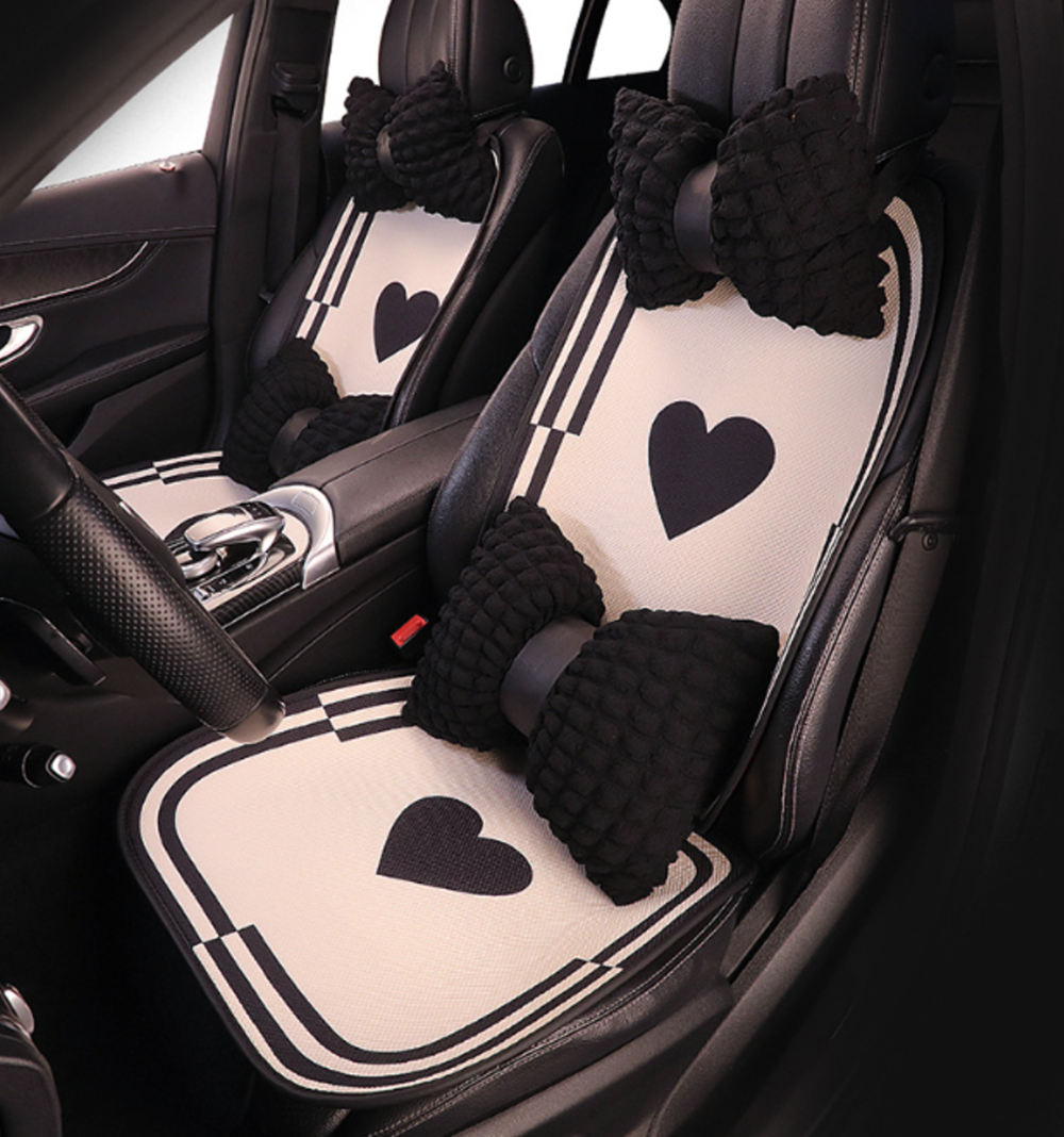 Breathable cartoon car seat cushions with heart pattern installed in BYD vehicle, featuring soft fabric and decorative bow-shaped pillows.