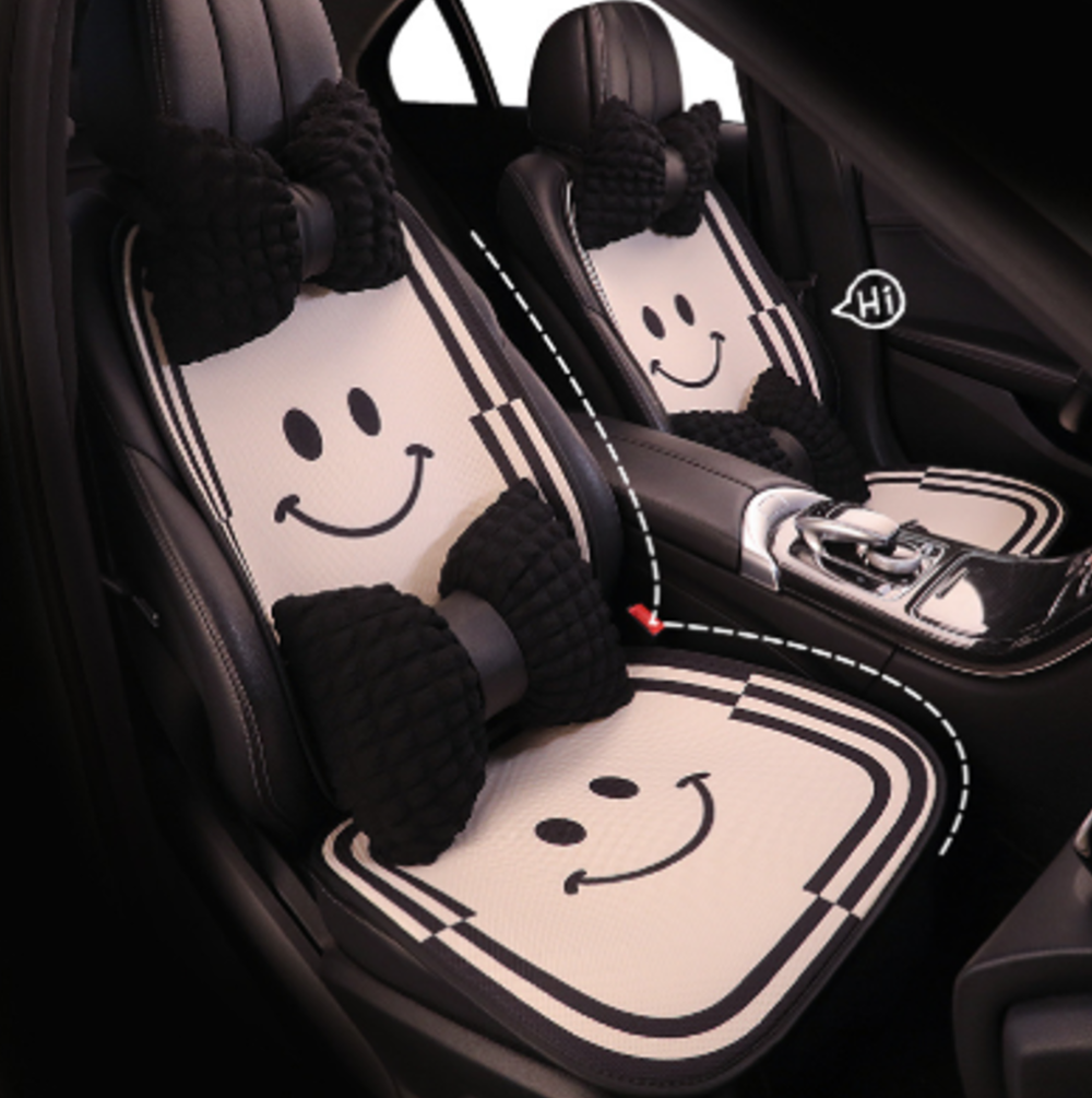 Breathable cartoon car seat cushions with smile face pattern installed in BYD vehicle, featuring soft fabric and decorative bow-shaped pillows.