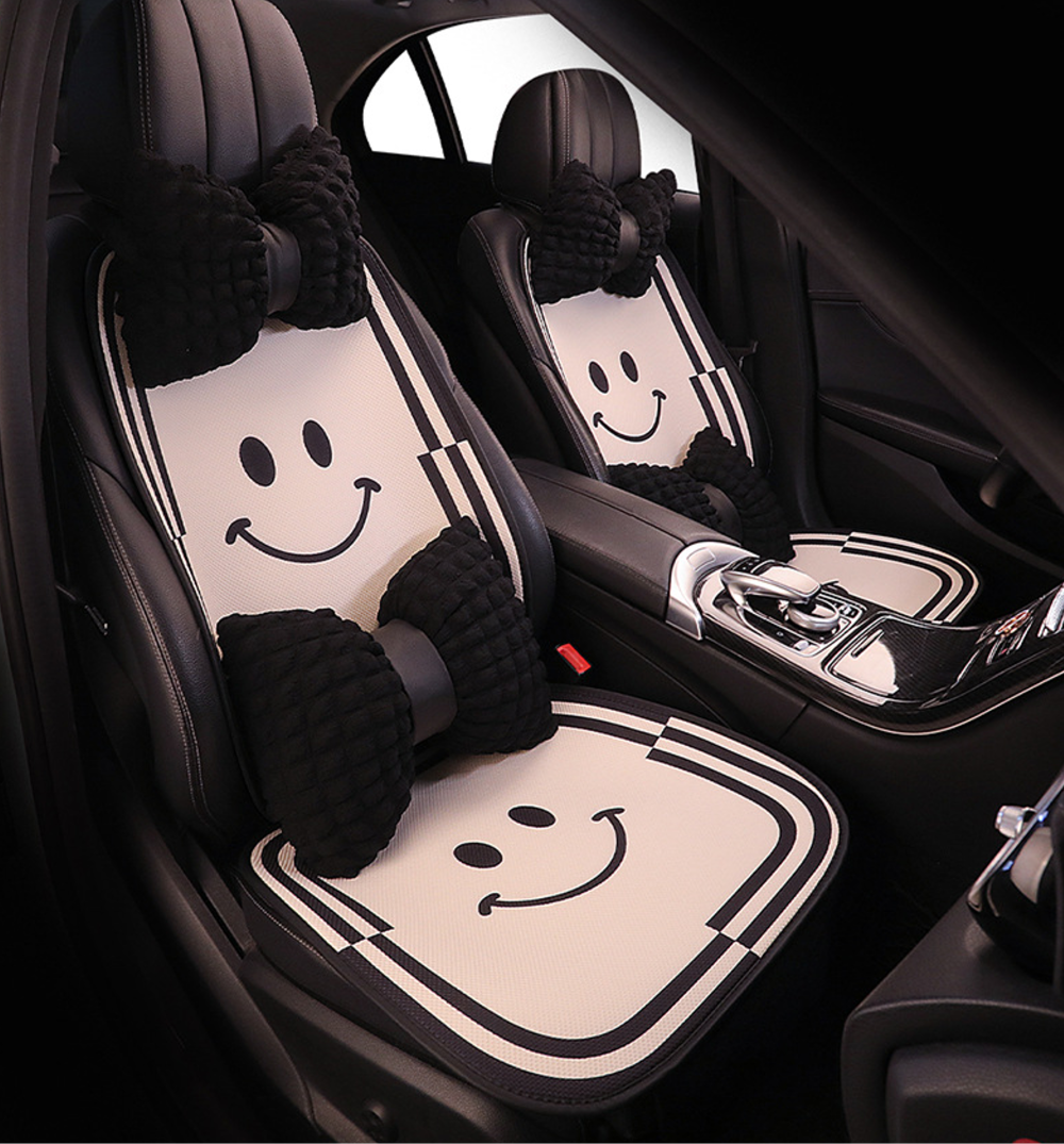 Front seat view of BYD cartoon-style car seat cushions featuring a smiling face pattern and black bow-shaped pillows, adding a playful and stylish touch to the car interior.