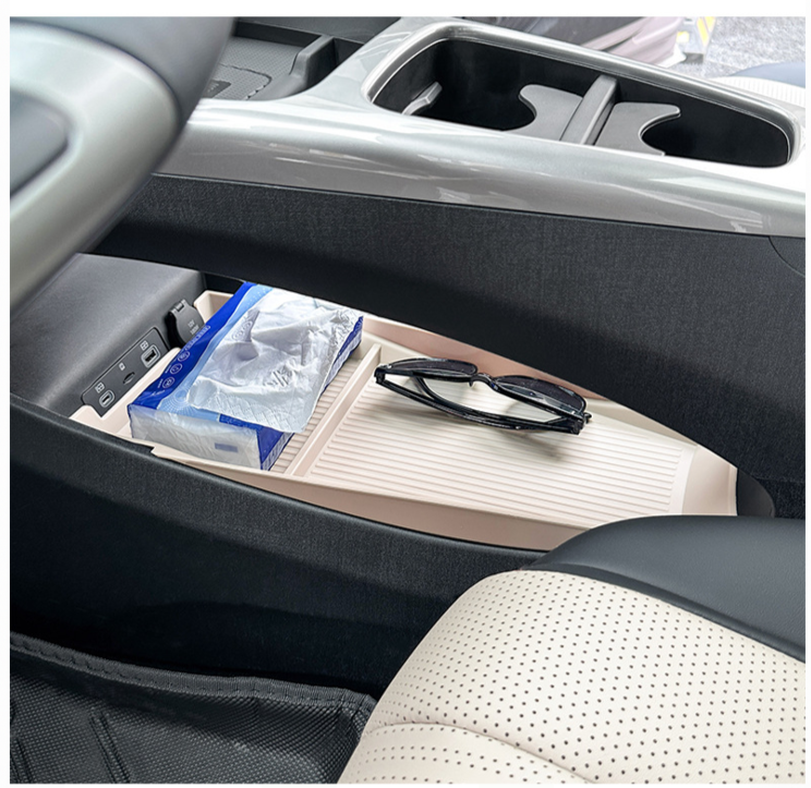 BYD Dolphin center console storage tray containing sunglasses and tissue pack, showing organized car interior accessories.