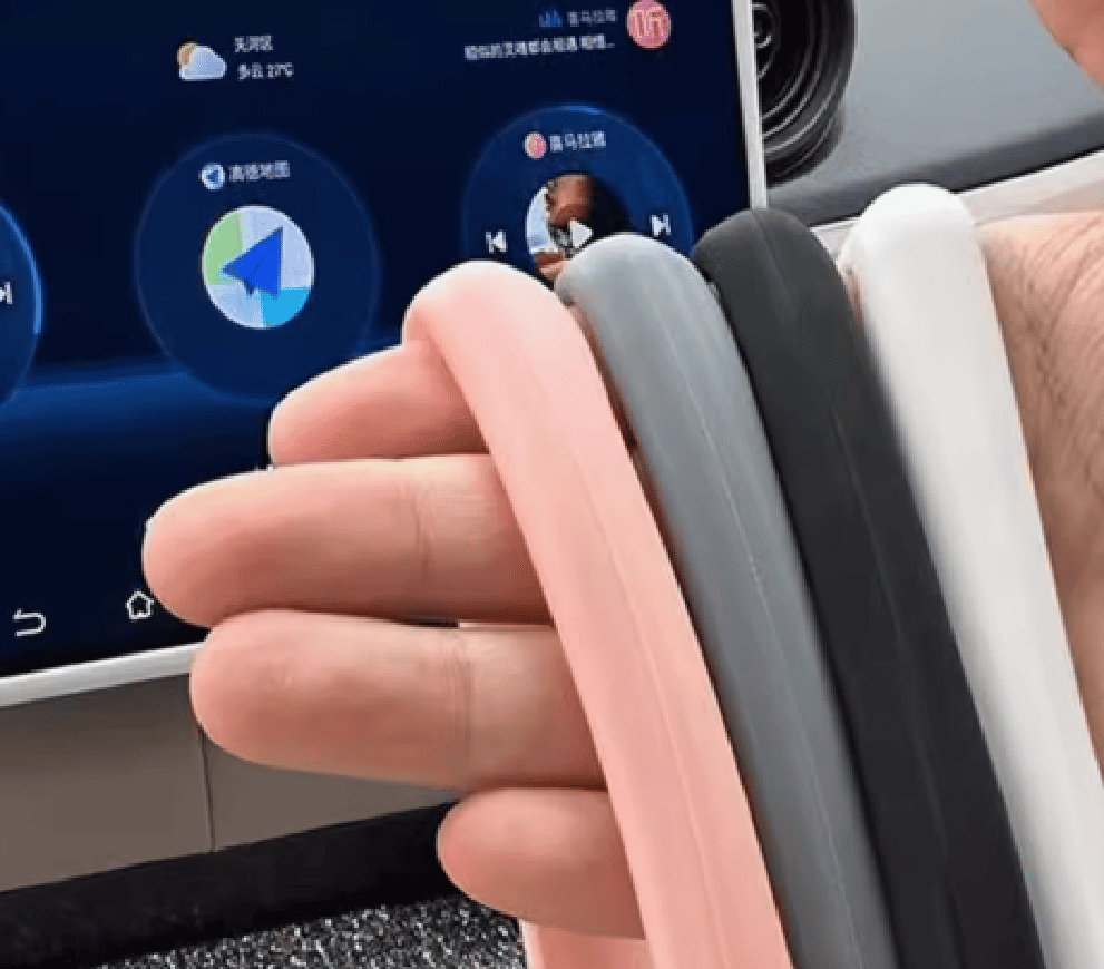Hand holding four color options of BYD screen trim: pink, grey, black, and white