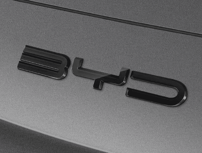 Side angle close-up of gloss black front bumper emblem decal installed on BYD Sealion 6, showcasing sleek 3D styling

