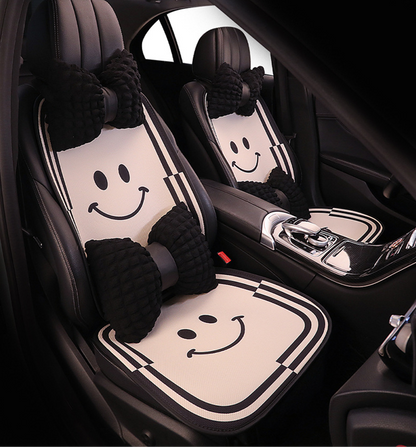 Front seat view of BYD cartoon-style car seat cushions featuring a smiling face pattern and black bow-shaped pillows, adding a playful and stylish touch to the car interior.