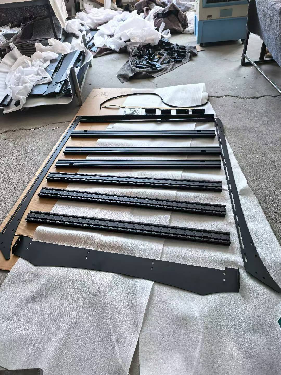 Disassembled roof rack platform for BYD Shark 6, including aluminum crossbars, steel side frames, and mounting brackets. Laid out for pre-installation view.