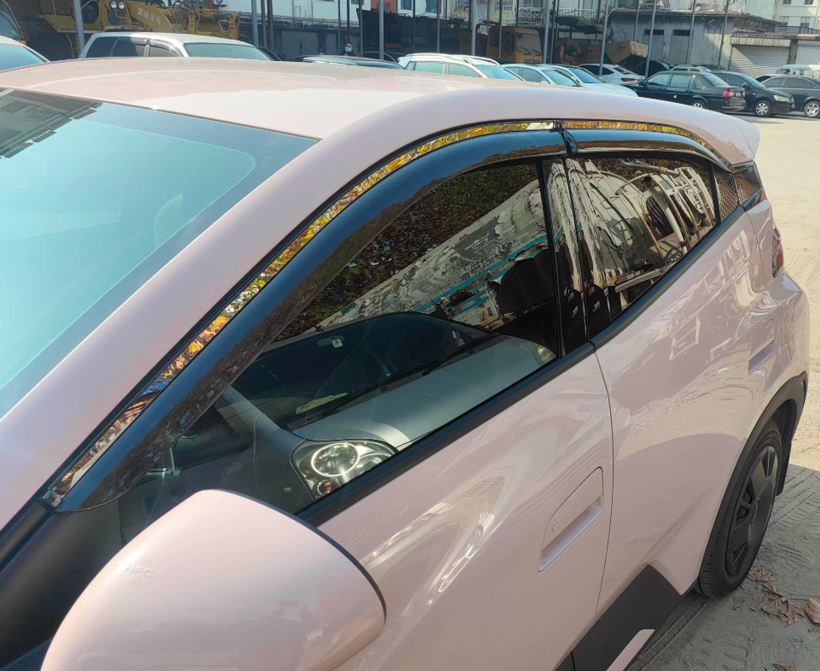 Front-angle view of BYD ATTO 1 window visors installed — dark tinted rain guards / wind deflectors with clean OEM-style fit along the window frame